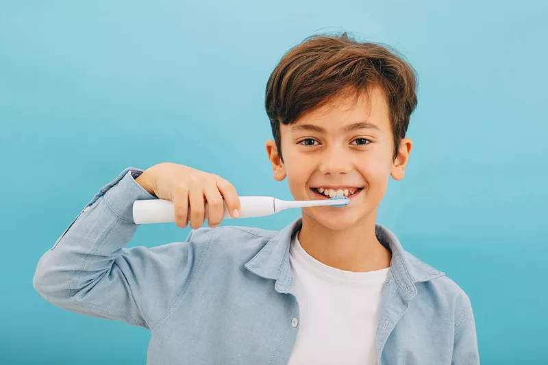 Chłopak myjący zęby szczoteczką soniczną